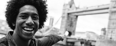 Retrato de jovem em viagem para Londres apontando para a London Bridge - Escritório Internacional